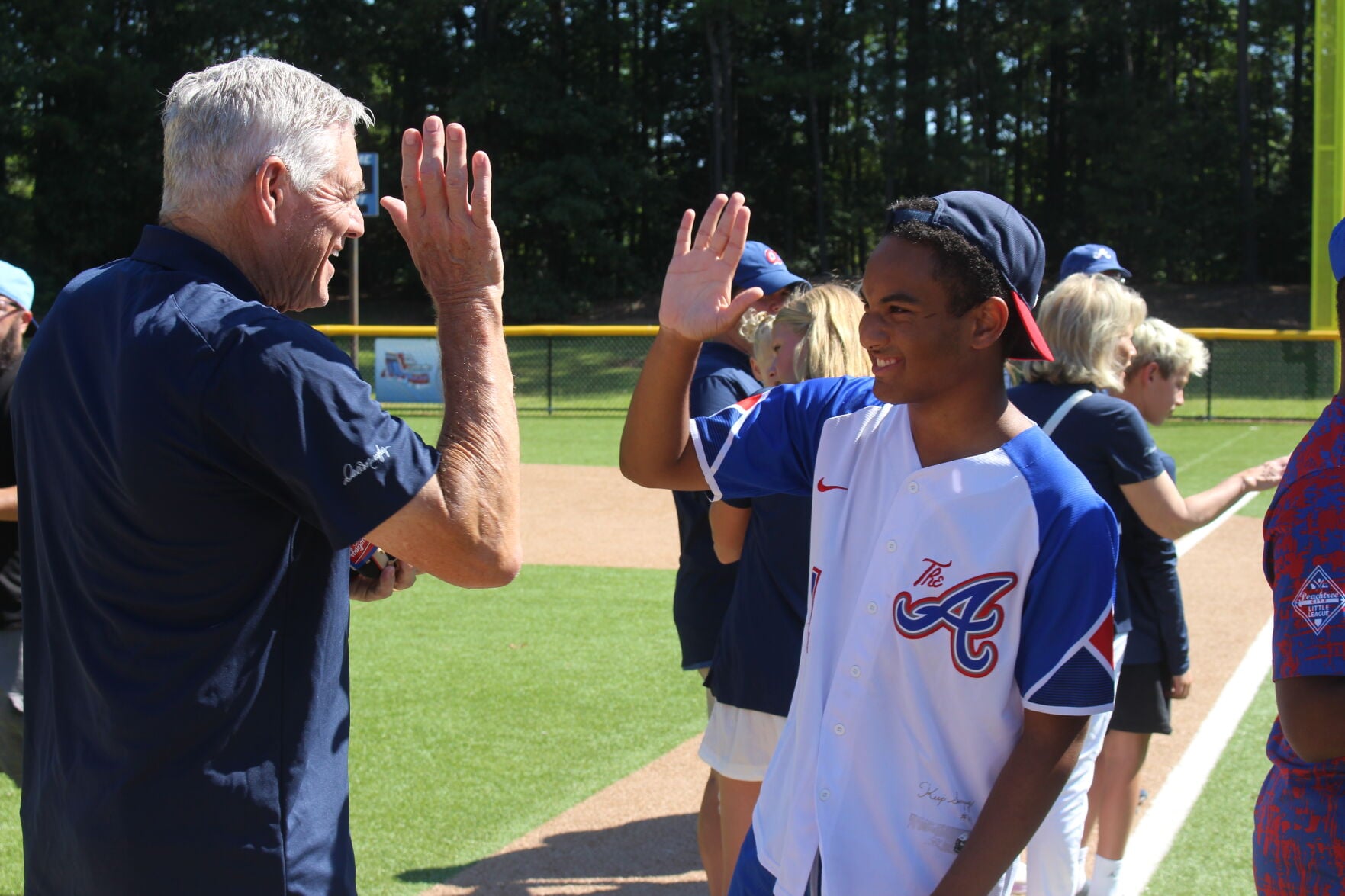Dale Murphy high-fives a Peachtree City Challenger League player wearing a baseball jersey